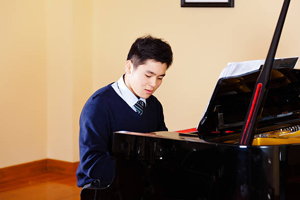 istock teenager boy playing piano 472133345