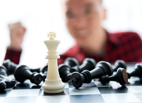Man laughing because he win the chess. the face in back and out of focus.