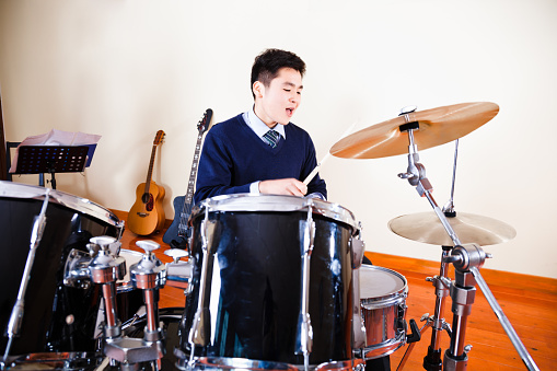 East asian teenage boy playing on a drum set