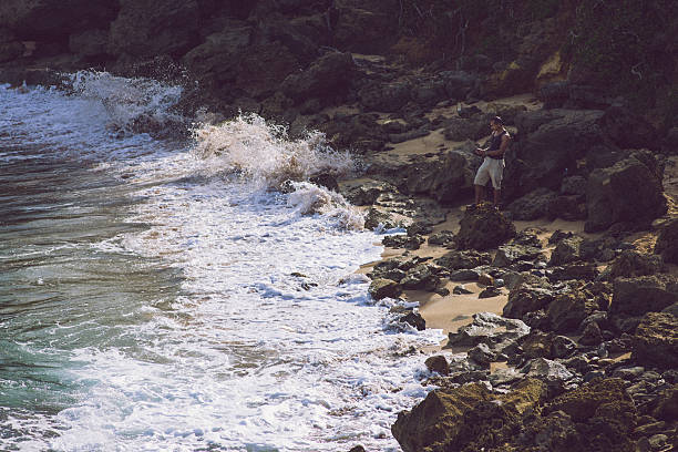 Hispanic man hiking and taking a picture with his smart phone at Cerro Gordo beach  located in Vega Alta, Puerto Rico