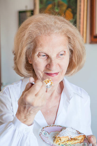istock Senior Woman Eating Cake Slice 472135379