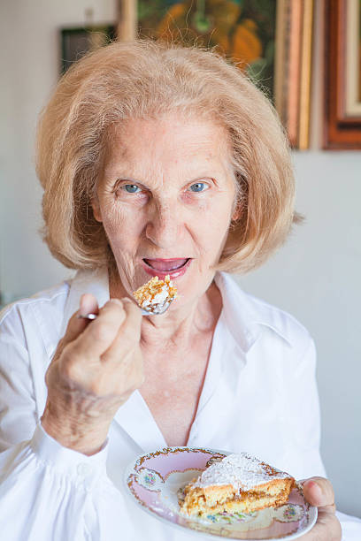 istock Senior Woman Eating Cake Slice 472135383