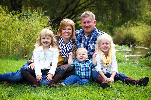 bella famiglia seduto accanto a flusso in erba verde - parker brothers foto e immagini stock