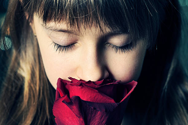 Beautiful little girl smelling a rose.