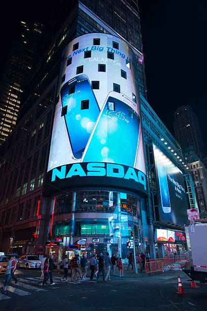 Nasdaq Stock Exchange New York City, USA - June 1, 2013: People walking outside the Nasdaq stock exchange billboard at Times Square Manhattan in New York City during night. retail digital signage stock pictures, royalty-free photos & images