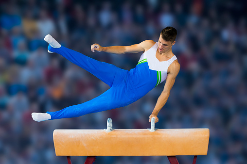 Front view of young male gymnast performing routine on the side horse