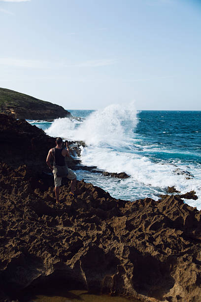 Hispanic man hiking during a vacation taking a picture with his smart phone at Cerro Gordo beach in Vega Alta, Puerto Rico.