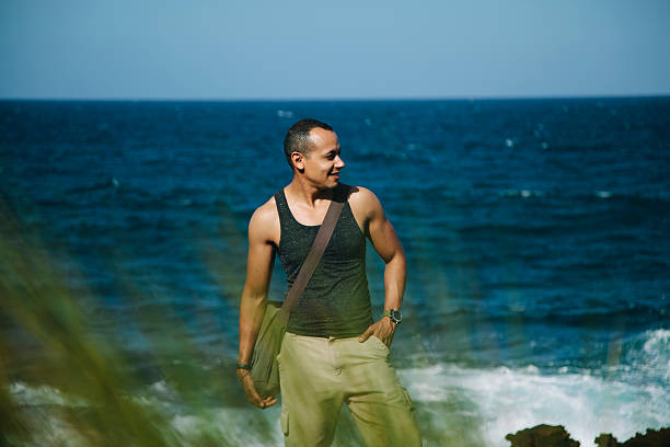 istock Latino male standing at the beach 472139689