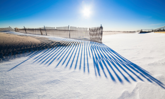 Jones Beach in winter: sand, snow, fences, sunlight and shadows.  