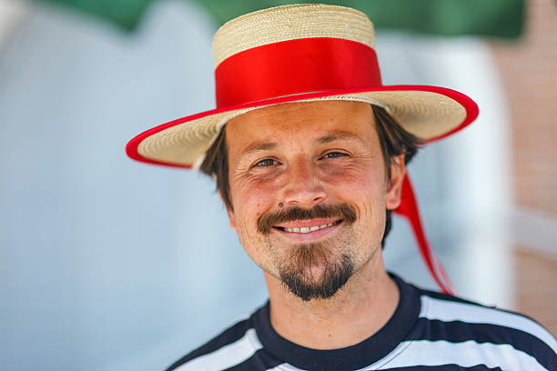 Venice, Italy - August 30, 2013: Portrait of a real smiling gondolier in Venice. Waiting for the customers by the gondolas.
