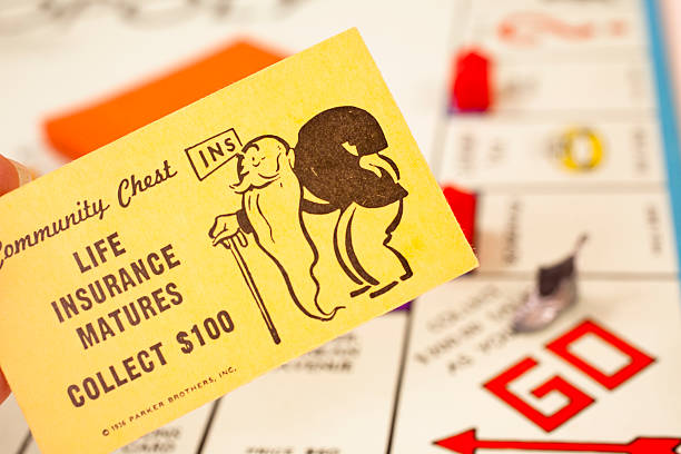 Conroe, USA - July 3, 2011: Close up of 'LIfe Insurance Matures' community chest card.  Monopoly board game in soft focus in background. Player with this card is to collect $100 from the 'bank'.  'Go' space in bottom corner. This game set is from the 1960s and Monopoly was patented in 1936 by Parker Brothers and has sold more than 275 million games worldwide.