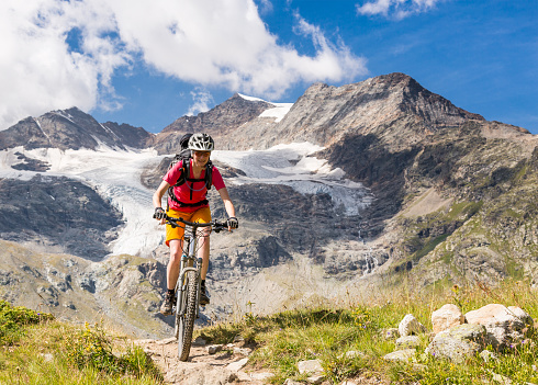 A female mountainbiker is riding in front of the magnificent scenery neerby the Bernina Pass (2328 mt, 7638 ft). In the background the  Piz Cambrena (3.606 mt, 11.830 ft.) is visible.