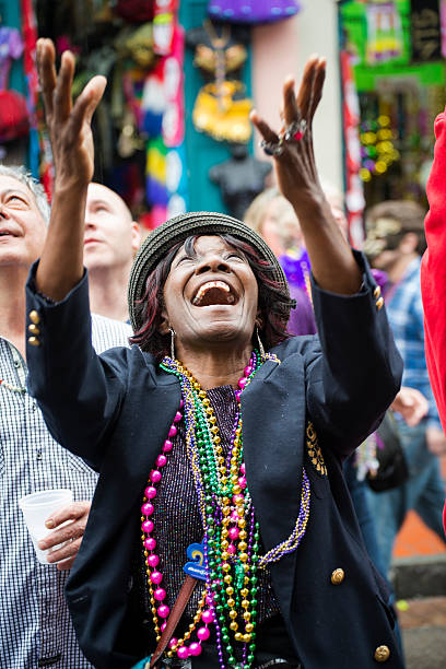 New Orleans, USA - February 12, 2013: An African American woman raises her arms and laughs while looking up toward a balcony on Bourbon Street during Mardi Gras 2013.
