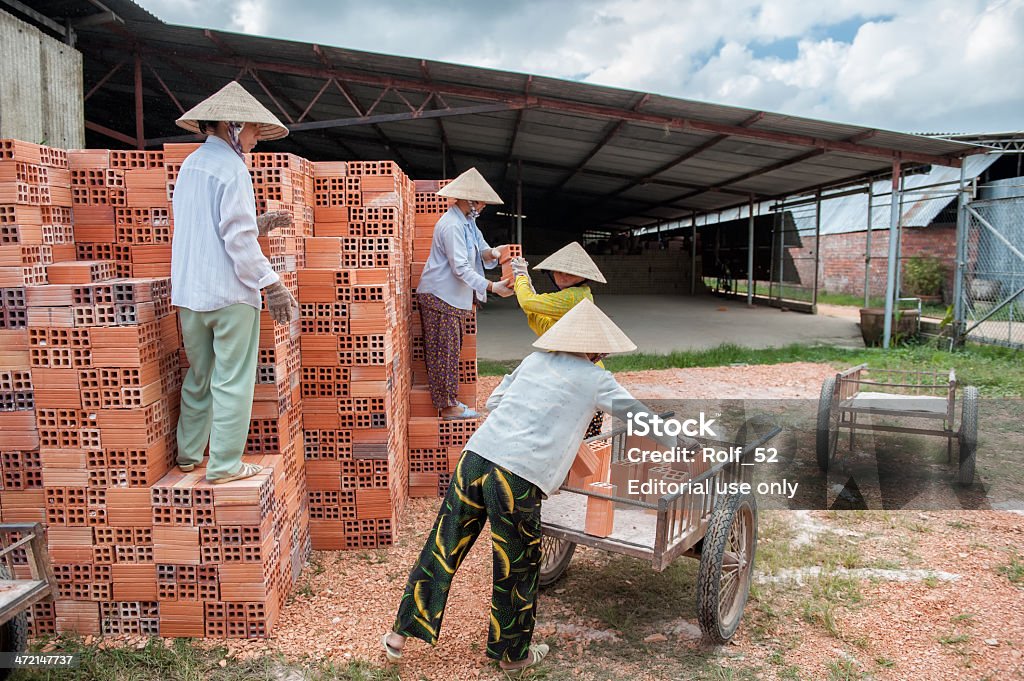 Vietnamese women working in a brickyard Vinh Long, Vietnam - March 7, 2009: Vietnamese women work in an old brickworks in the Mekong delta. The Mekong delta has become popular among tourists wishing to experience rural Vietnam. Adult Stock Photo