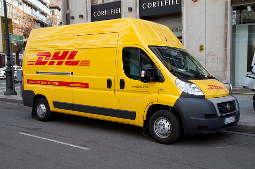 Valencia, Spain - January 28, 2014: A DHL delivery van on the street in the city center of Valencia. DHL is a world wide courier company that operates in 220 countries with over 285,000 employees.