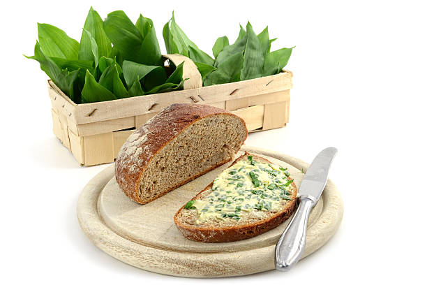 herb butter wild garlic (Allium ursinum) on slice of bread herb butter wild garlic (Allium ursinum) on slice of bread at wooden cutting board. in background a basket on white isolated background zigeunerlauch stock pictures, royalty-free photos & images