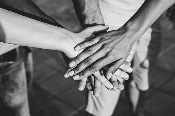 All together Hands stacked in unity and support. Multiethnic group of people. Black and white picture. stacked hands photos stock pictures, royalty-free photos & images