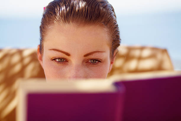 Close up with female's hands holding book that have Frangipani flowers is a bookmark, Reading book, Outdoors.