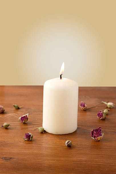 istock burning candle on a table scattered with flowers 472153156