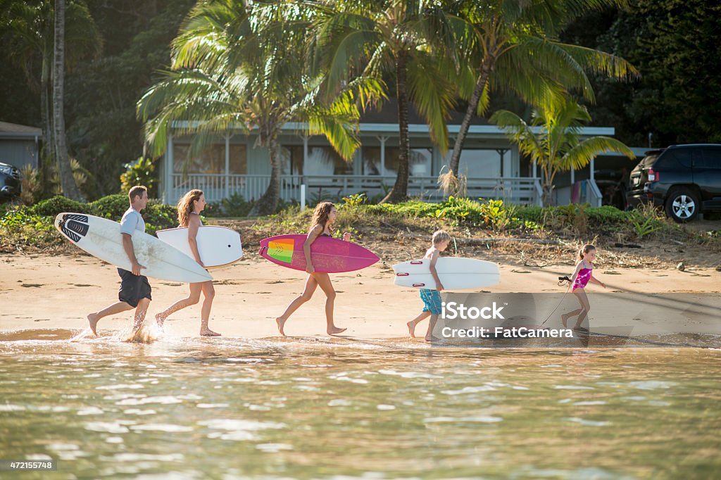 Family on Vacation in the Tropics An active family on vacation in Hawaii at the beach on a sunny day going surfing and bodyboarding. Family Stock Photo