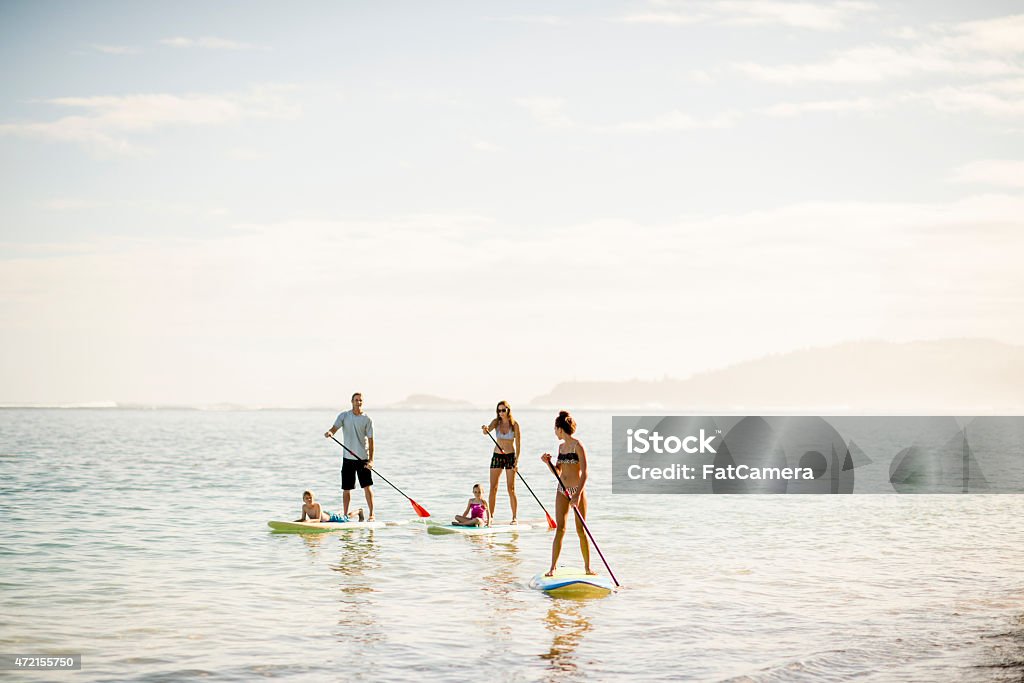 Beautiful Scenery when Paddleboarding A multi-ethnic family on vacation in the ocean stand up paddle boarding together on a sunny day in Hawaii. Family Stock Photo