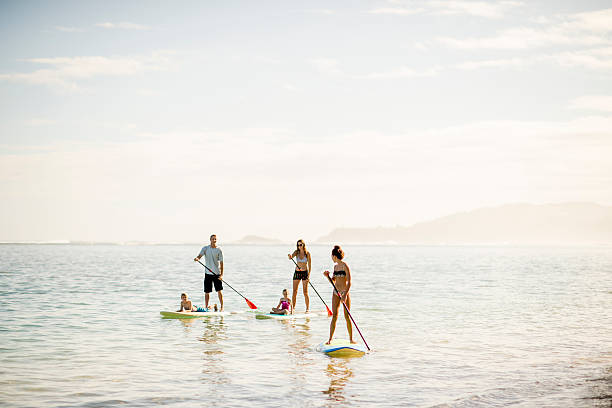 Beautiful Scenery when Paddleboarding A multi-ethnic family on vacation in the ocean stand up paddle boarding together on a sunny day in Hawaii. paddleboard surfing oar water sport stock pictures, royalty-free photos & images