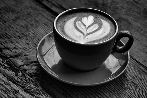 Low key, high contrast image of a cup of Latte in black and white.