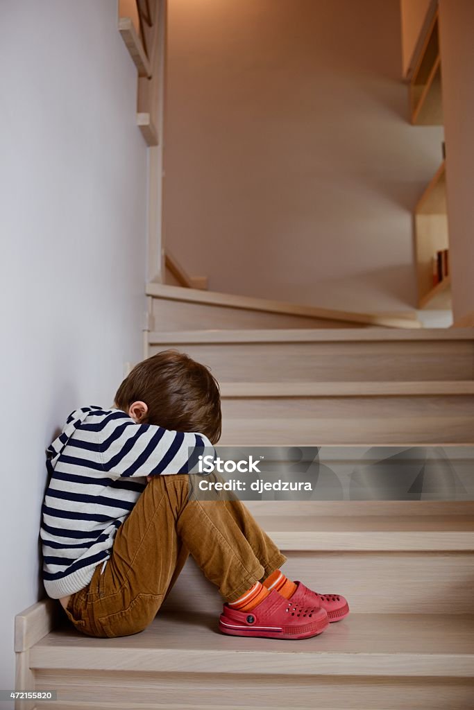 Sad little boy crying depressed sitting Sad little boy crying depressed sitting on the stairs Crying Stock Photo