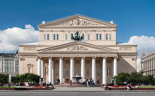 Moscow, Russia - August 19, 2012: The facade of the Bolshoi Theatre and walking pedestrians. The Bolshoi Theatre is a historic theatre in Moscow, designed by architect Joseph Bove, which holds performances of ballet and opera.