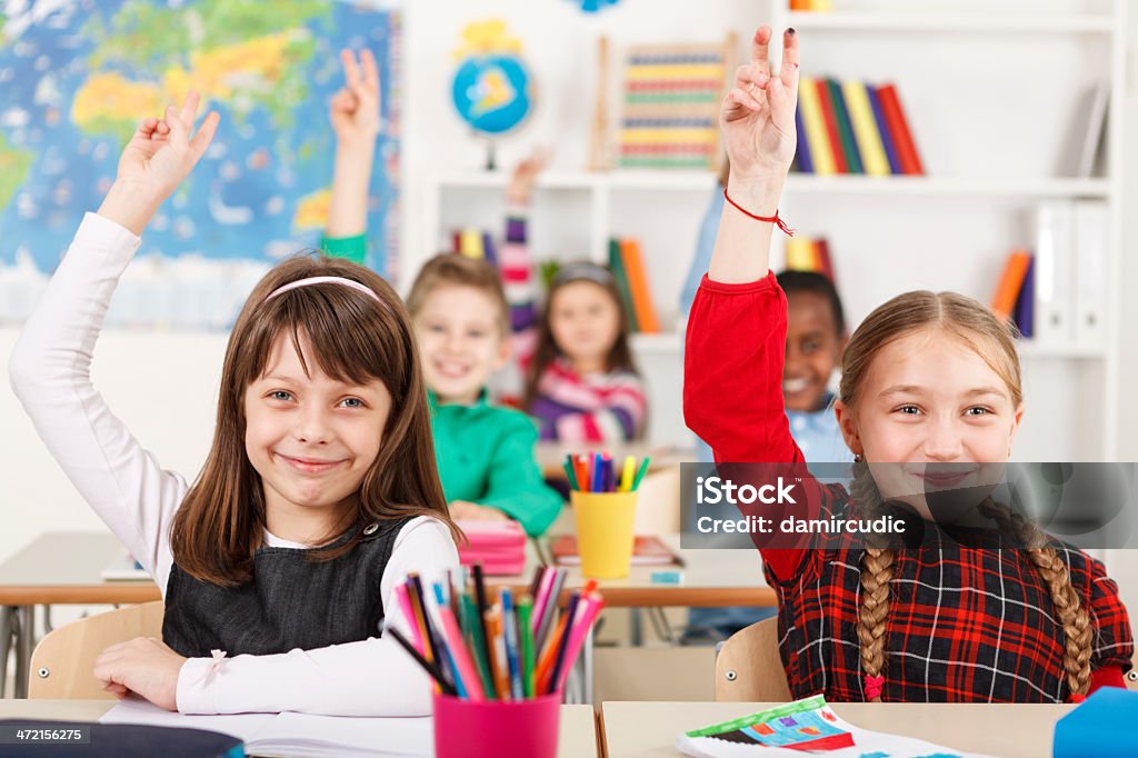 School Children With Raised Hands In Classroom Classroom Stock Photo
