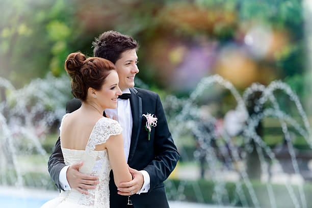 beautiful wedding couple smiling, water fountain in background.