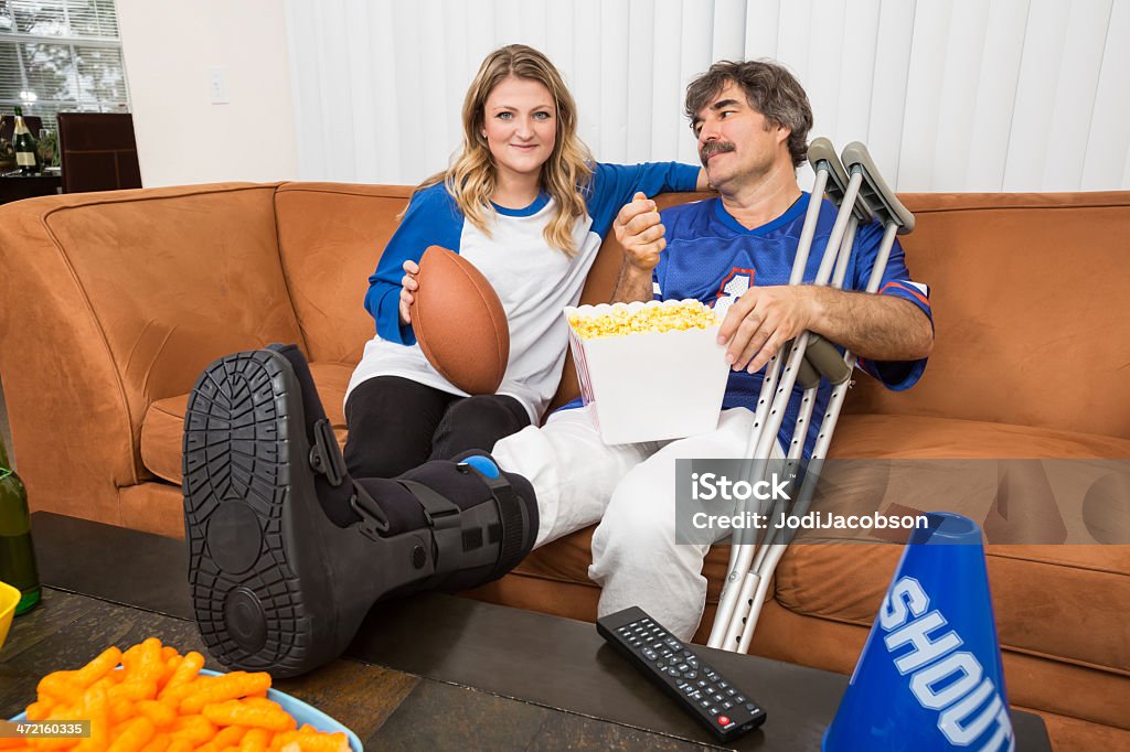 男性、負傷した脚とガールフレンドのフットボール観戦 - おやつのロイヤリティフリーストックフォト