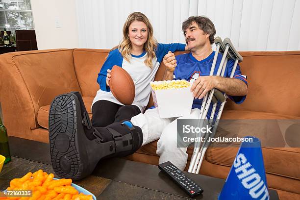 男性負傷した脚とガールフレンドのフットボール観戦 - おやつのストックフォトや画像を多数ご用意 - おやつ, アメフトボール, アメリカンフットボール