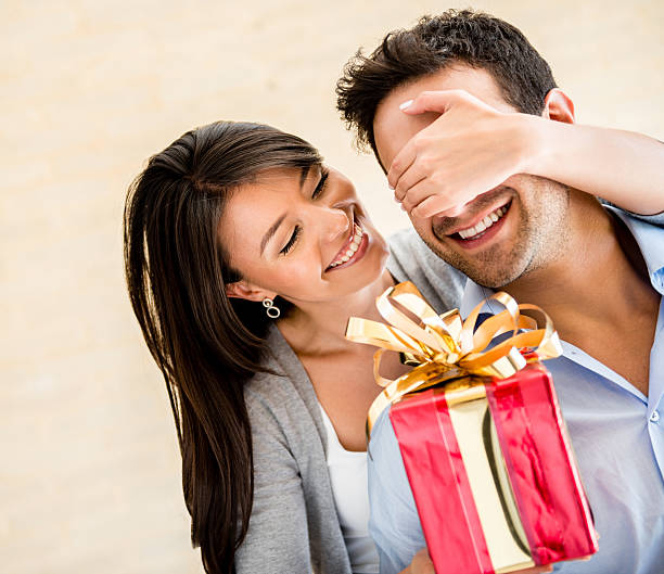 Young multi-ethnic couple smiling and holding heart shaped gift