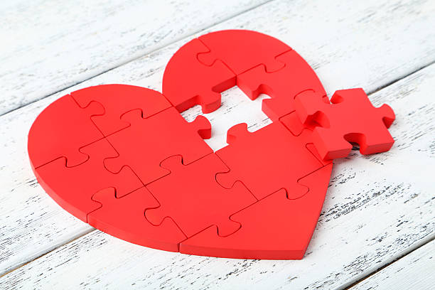istock Red puzzle heart on white wooden background 472162382