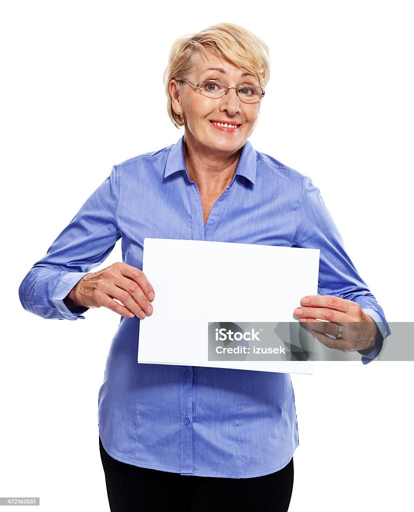 Senior businesswoman Portrait of smiling senior businesswoman holding a white piece of paper. Studio shot, white background. Holding Stock Photo