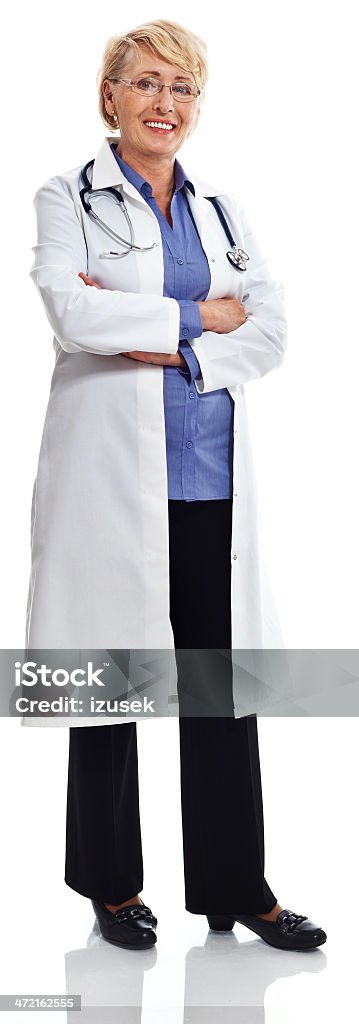 Mature Smiling Female Doctor, Studio Portrait Full lenght portrait of a mature female doctor standing with arms crossed and smiling at camera. Studio shot on a white background. Doctor Stock Photo