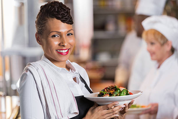 istock Waitress holding customer's order in restaurant kitchen; smiling at camera 472163119