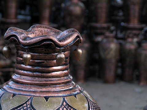 Focus on a traditional copper vessel with a number of vessels in the background.
