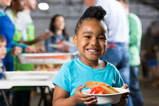 little girl holding bowl en cocina libre o banco de alimentos - comida básica fotografías e imágenes de stock