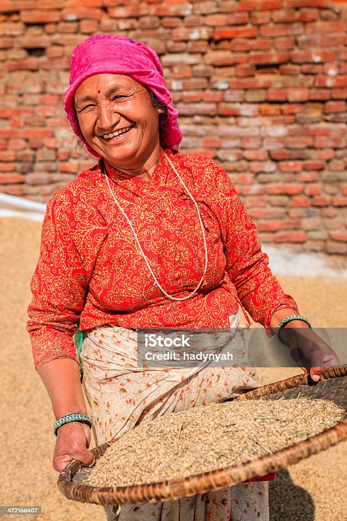 Nepali woman sifting a rice Nepali woman drying grain in Bhaktapurhttp://bem.2be.pl/IS/nepal_380.jpg Adult Stock Photo