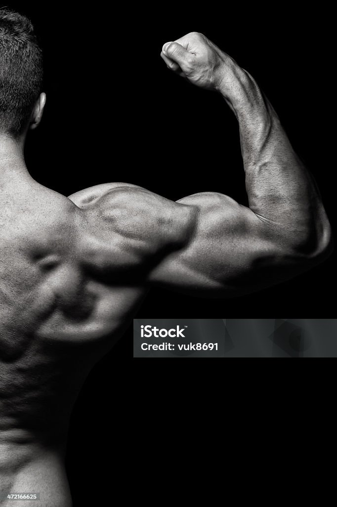 Big gun Body builder flexing biceps in front of black background Adult Stock Photo