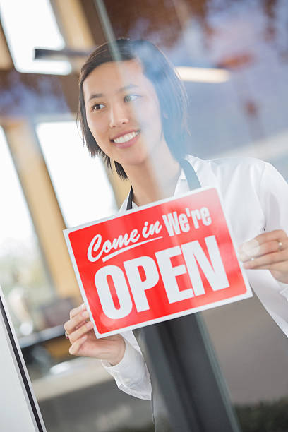 istock Happy waitress placing OPEN sign in restaurant window 472168307