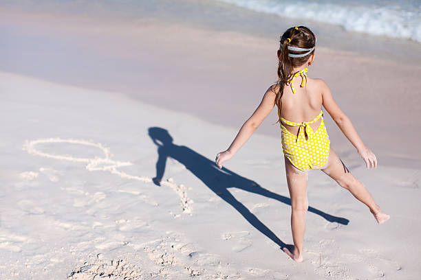 Child walking on  the beach in her swimingsuit and and enjoys the sunset