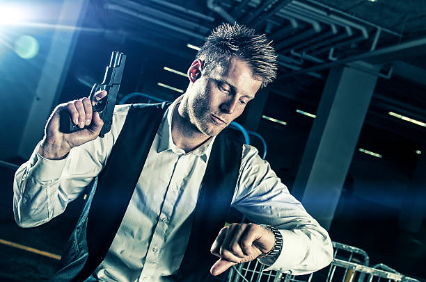 istock Man with gun looks at a watch 472170383