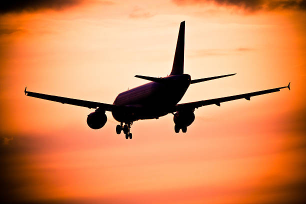 istock Airplane landing at sunset 472170397