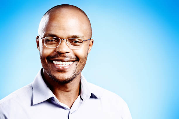 istock Confident young man in spectacles smiling happily against blue background 472171353