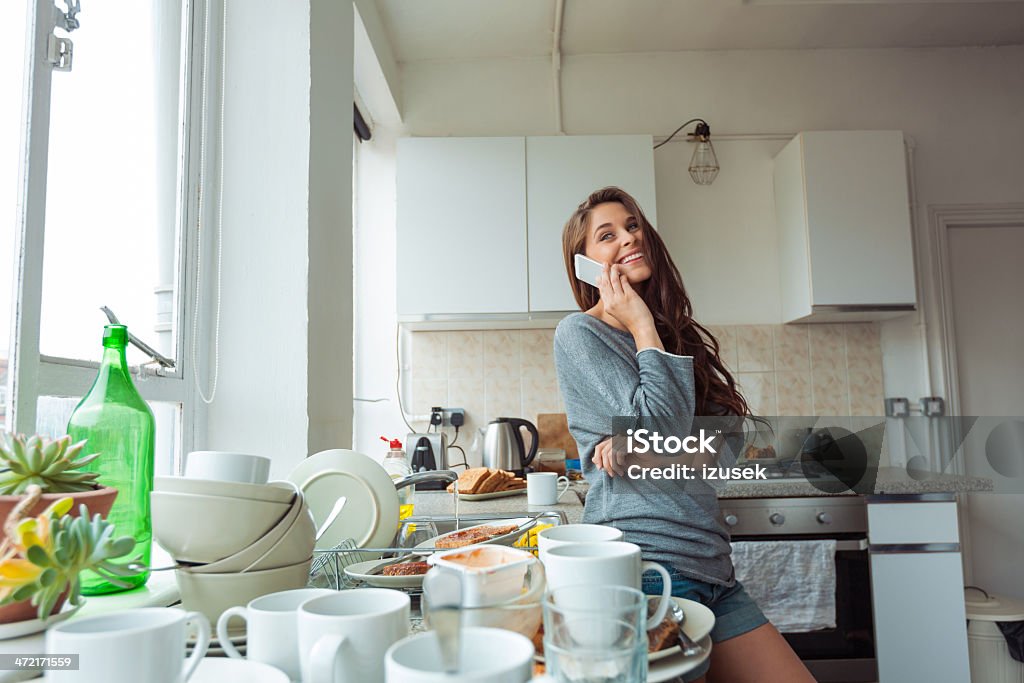 Woman washing dishes Young woman going to cleaning kitchen, standing next to sink and talking on phone. Kitchen Stock Photo