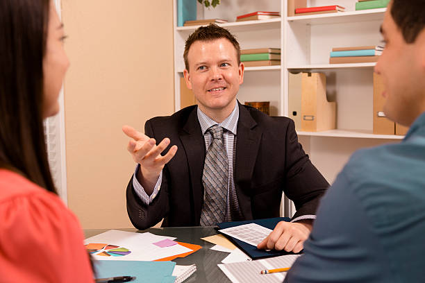 istock Business: Latin couple reviews financial documents with advisor. 472172145