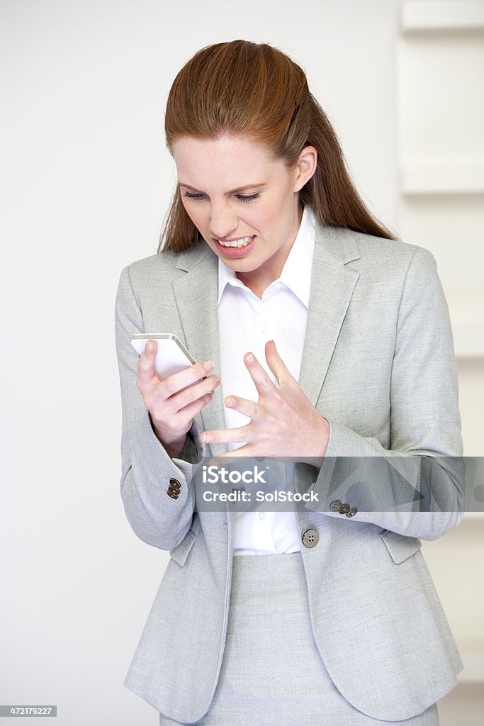 Businesswoman using a mobile telephone Businesswoman holds and looks at his mobile telephone. With her fingers splayed on her free hand, her face twists as she looks angry 30-39 Years Stock Photo